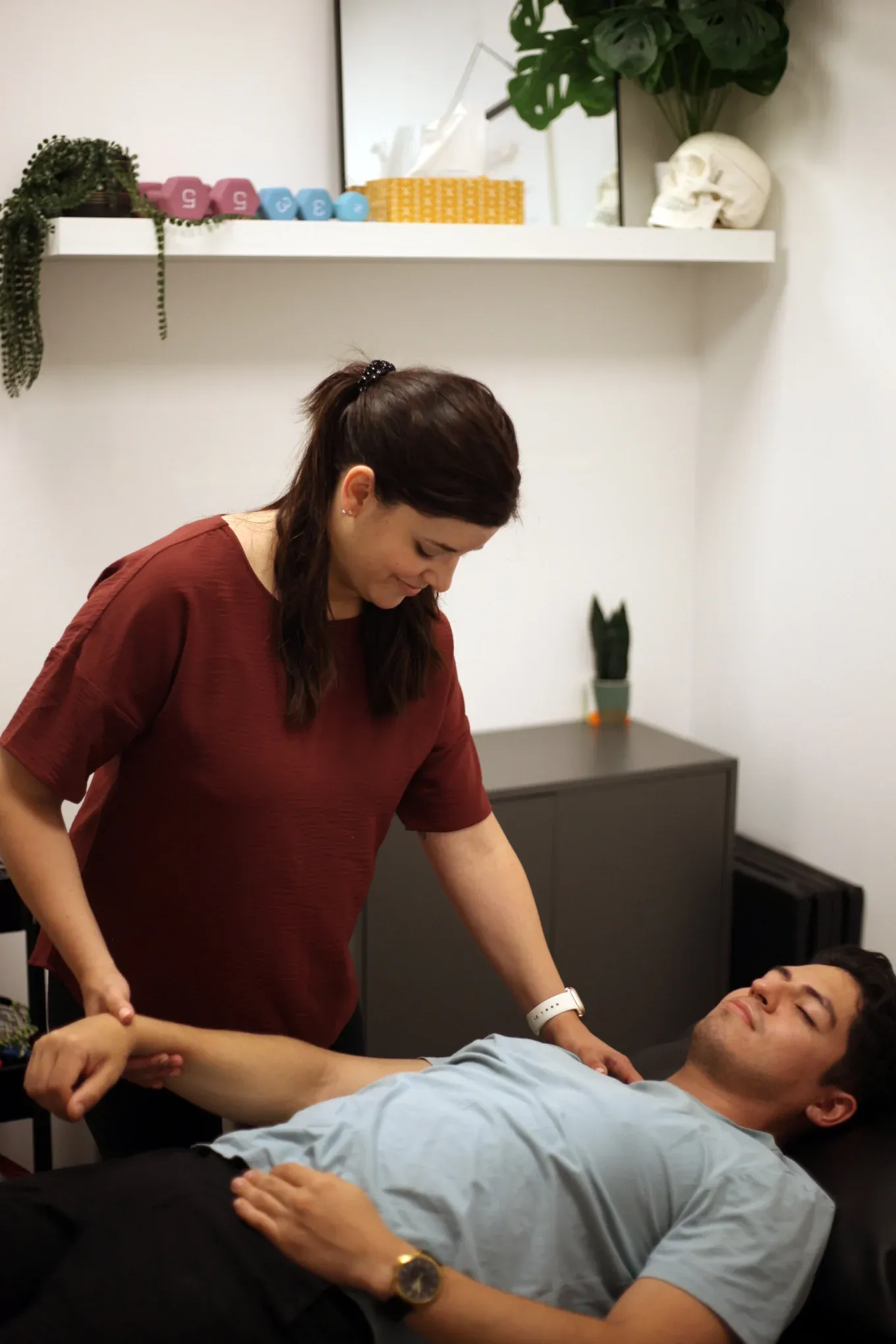 Dr. Natalie providing hands-on shoulder and arm care to a patient in a clinic room.