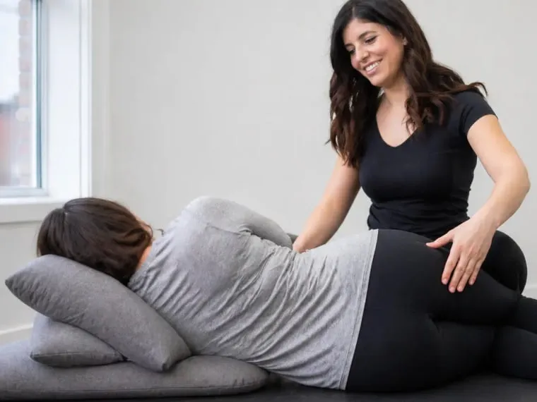 A pregnant patient lying on their side, supported by pillows, during treatment.